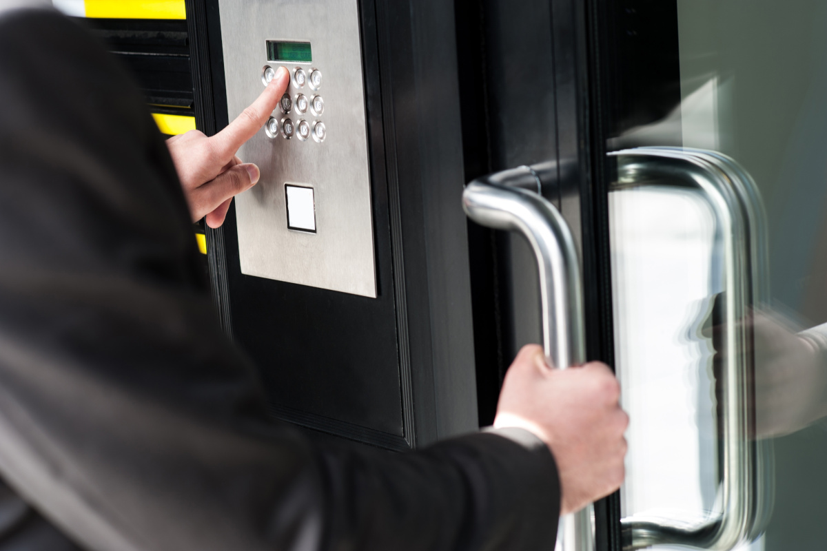 A person entering a code on a keypad to unlock a door