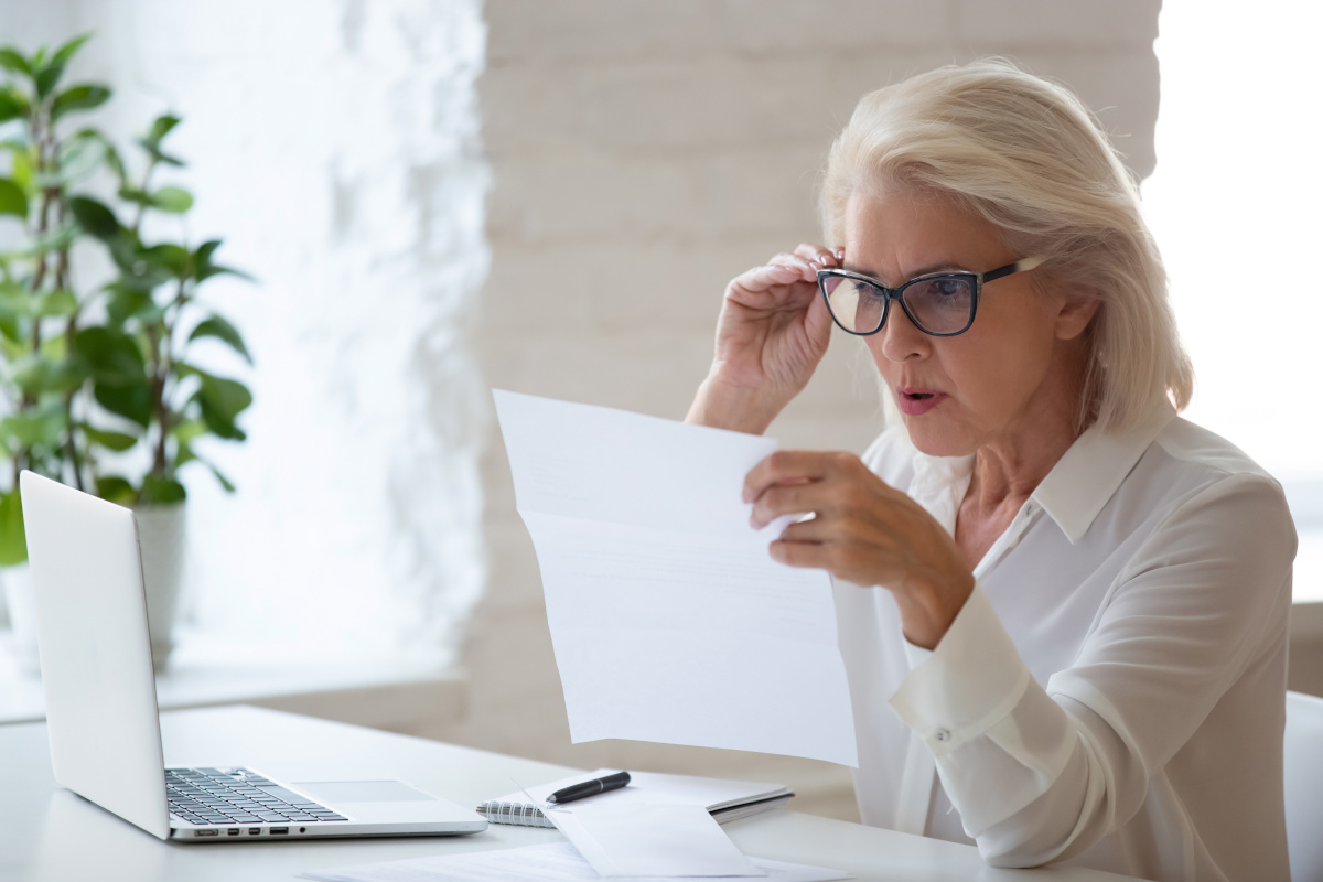 A woman looking at a paper document in surprise