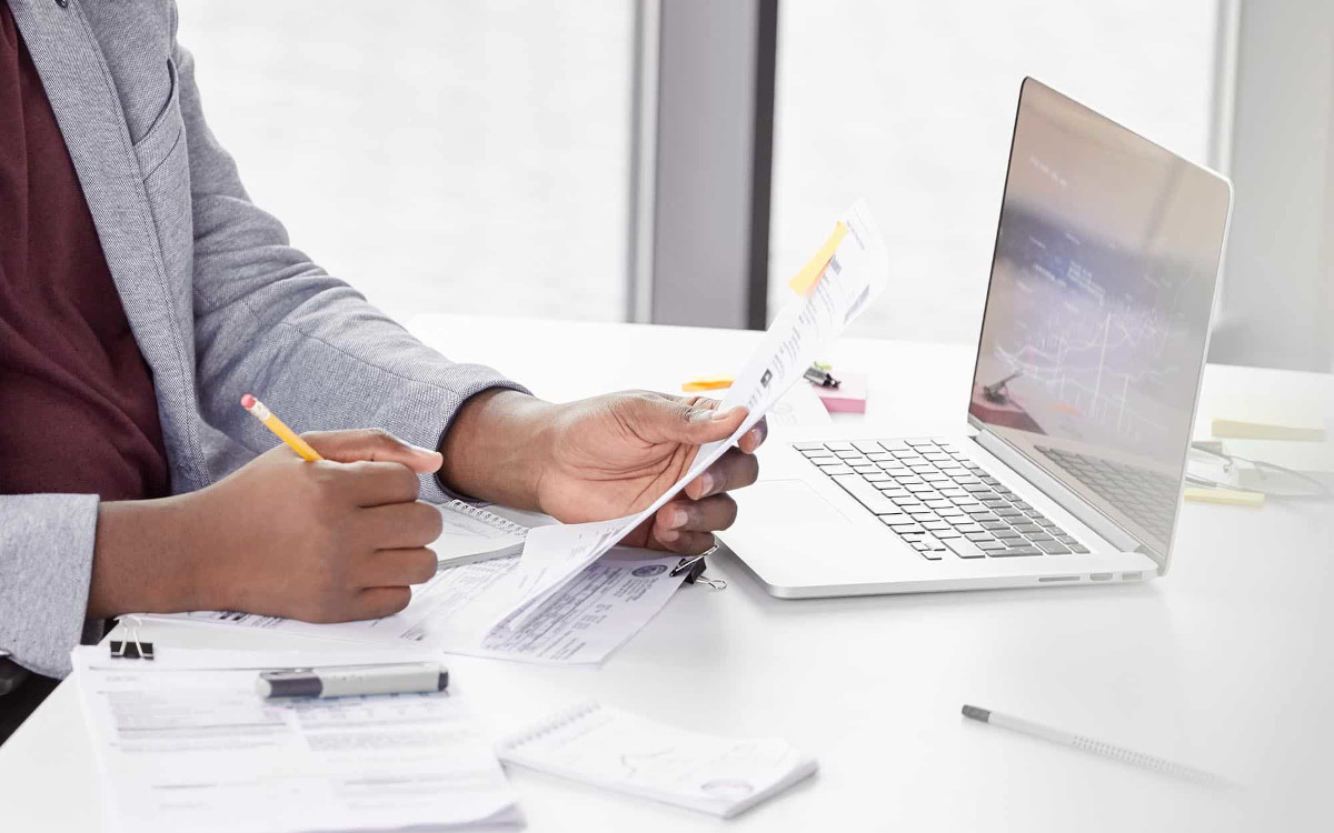 Man working on laptop and looking at documents