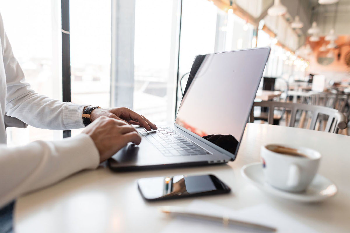Man working on laptop with a cup of coffe next to him