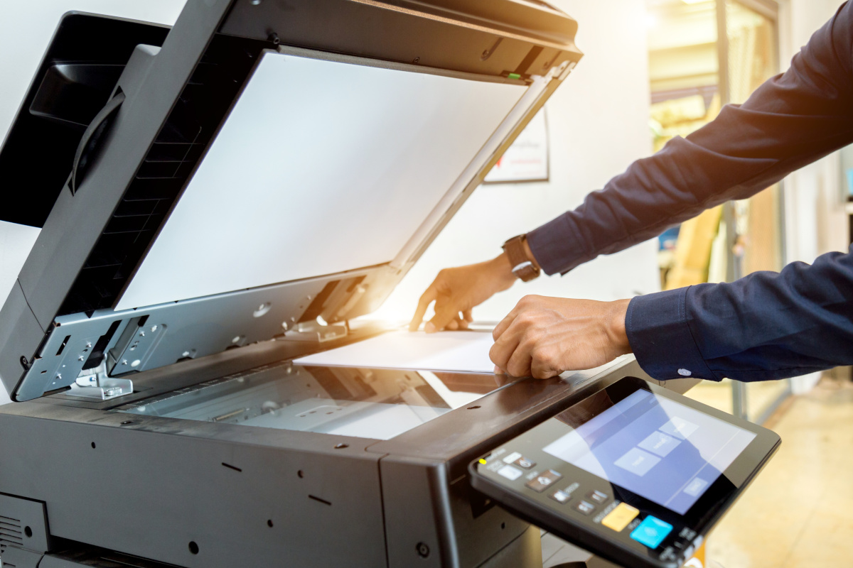 person using a high tech printer with light shining from the office window