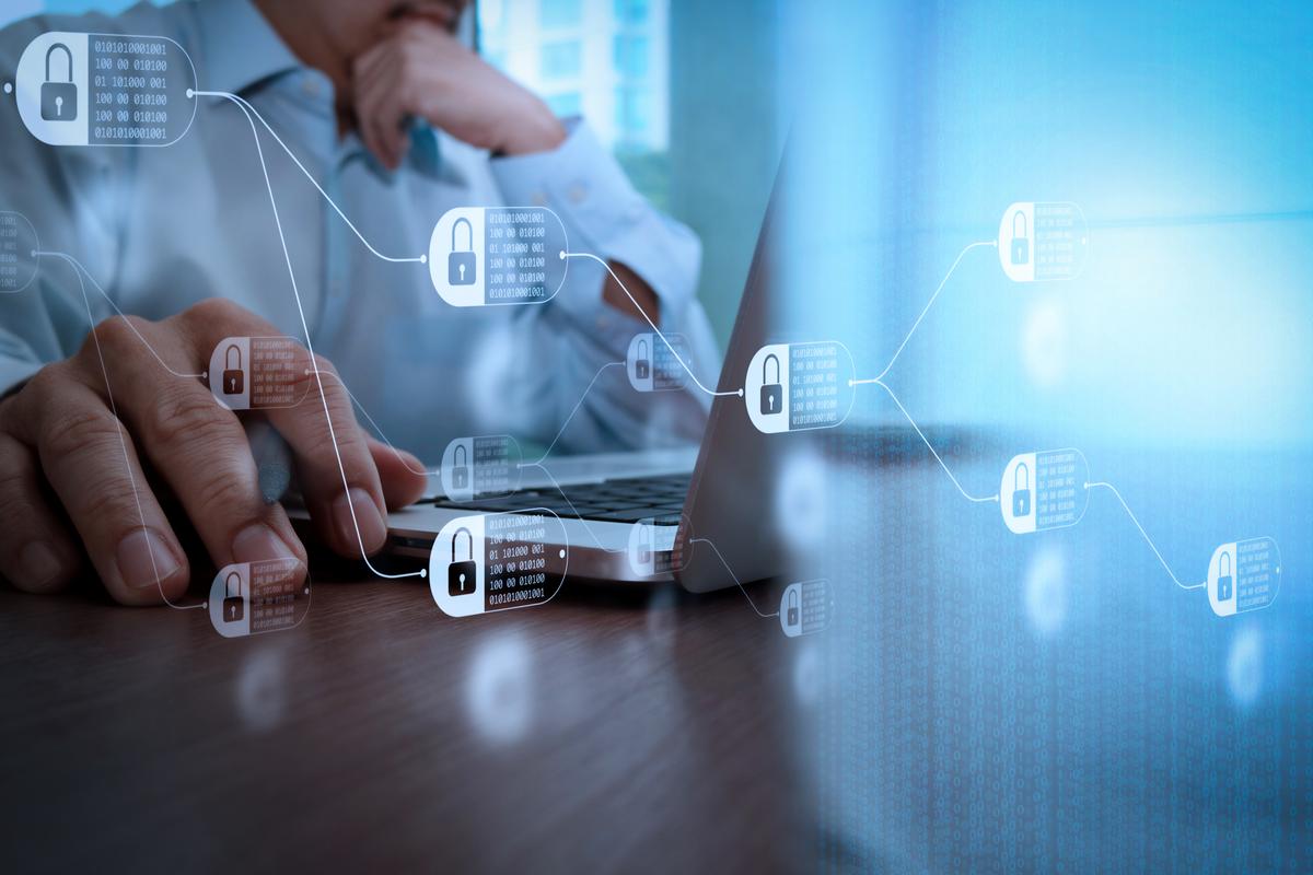 Man working on laptop with digital access denied icons floating around