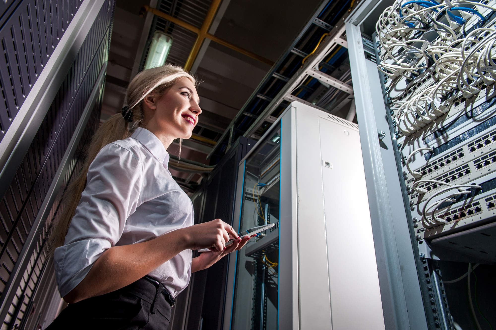 Data center technician using tablet in front of servers